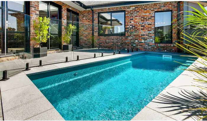 Rechteckiger Pool – klares blaues Wasser, gepflegte Hecken und Steinpflaster