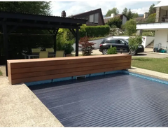 Pool-Rollladenabdeckung – dunkelblaue gerippte Oberfläche, Holzbank daneben, 60 x 14 mm