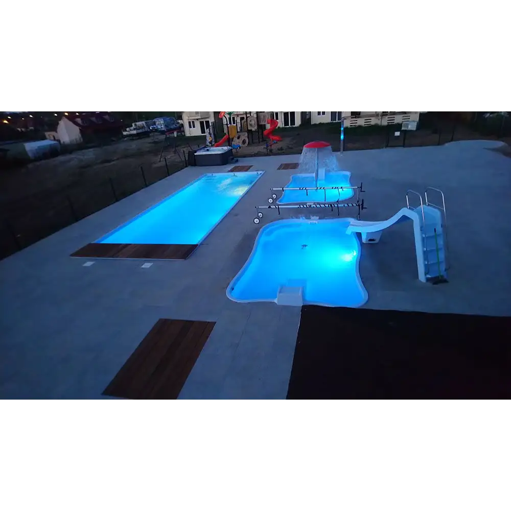 Blå upplyst Bahama trädgårdspool med rutschkanor, vattenfall och transparent pooltak