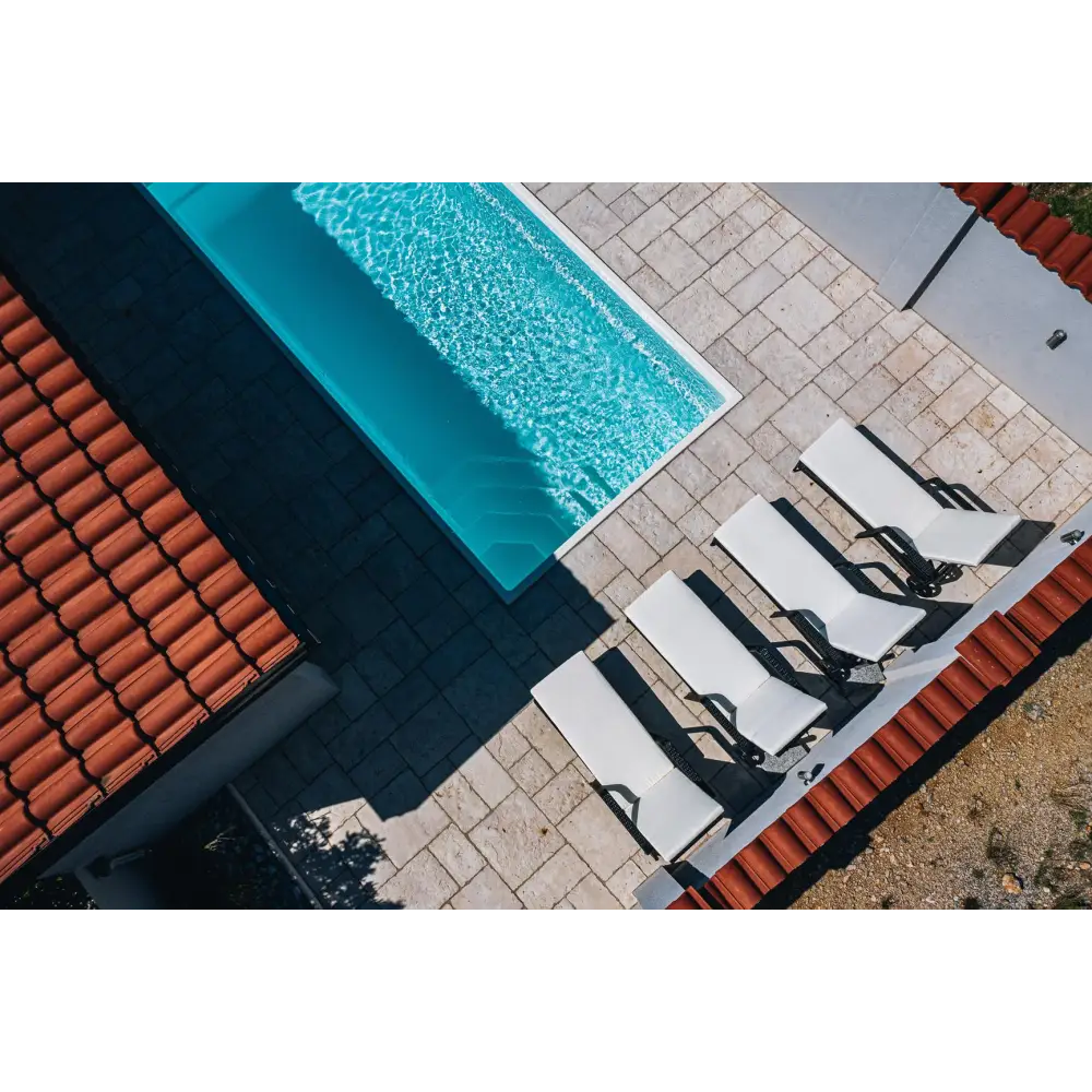 Glasfiberpool Saba med turkost vatten och vita kaklade kanter