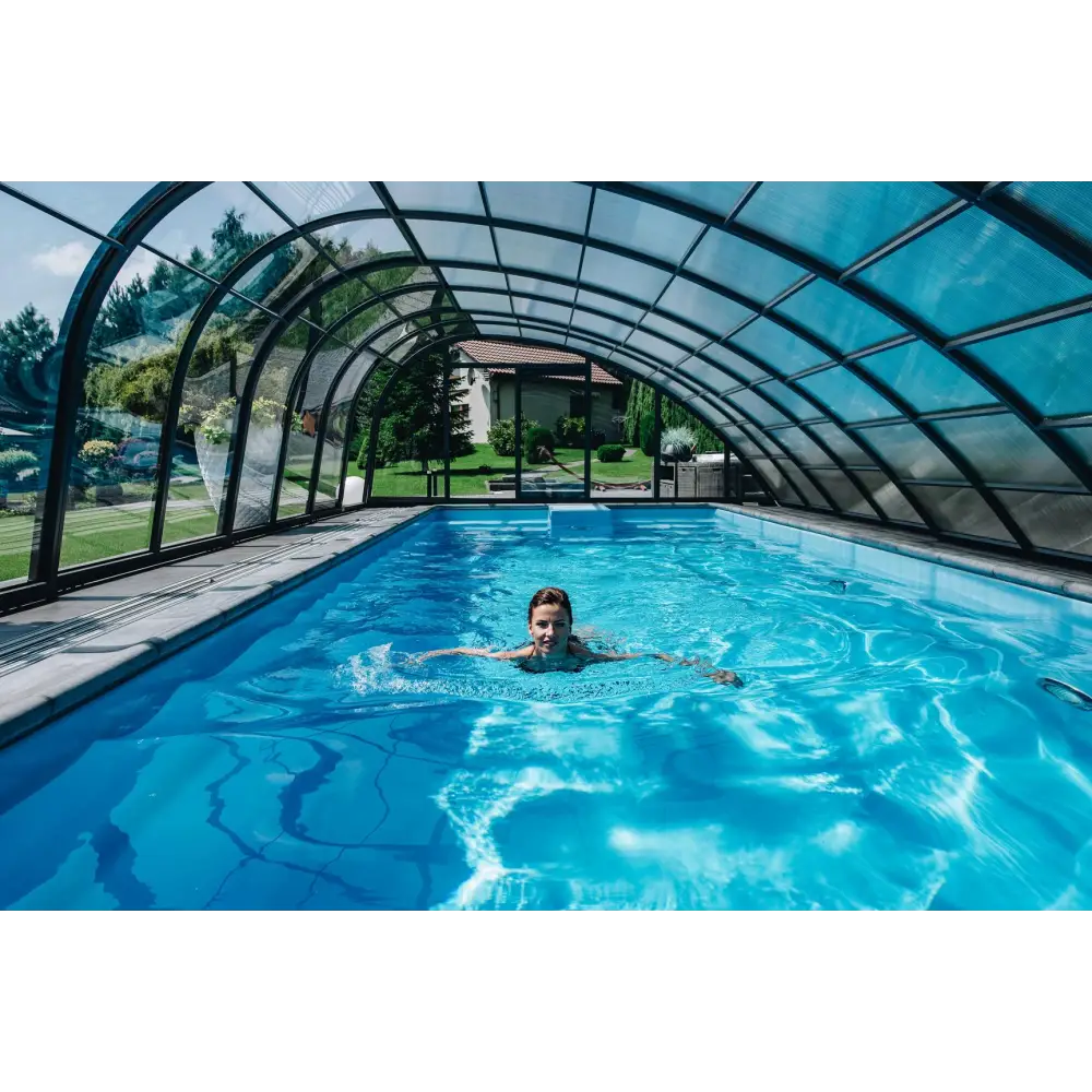 Kvinna simmar i glasfiberpool Trinidad med blå kakel och inbyggt poolöverdrag under glastak