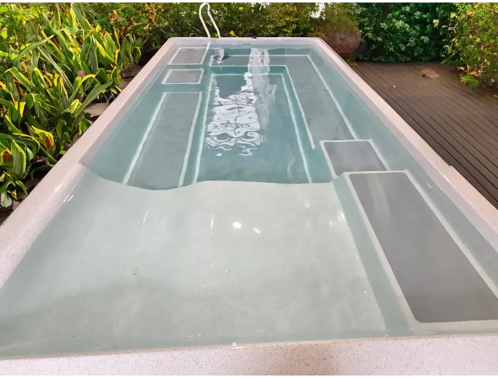 Rektangulär fiberglasspool Mira390 med ljusgrå interiör, inbyggda steg och grön omgivning för wellness pool ovanmark