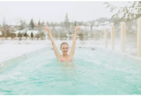 PassionSpa Activity 2 Swim-Spa – lächelnde Frau im pinken Bikinioberteil mit erhobenen Armen, von Schnee umgeben