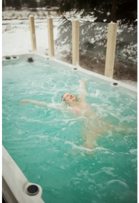 PassionSpa Activity 2 Swim-Spa – Frau im pinken Bikini treibt ruhig im Wasser, von Schnee umgeben