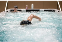 PassionSpa Aquatic 2 Swim-Spa – Schwimmer mit schwarzer Badekappe mit gelbem Rand, sprudelndes Wasser