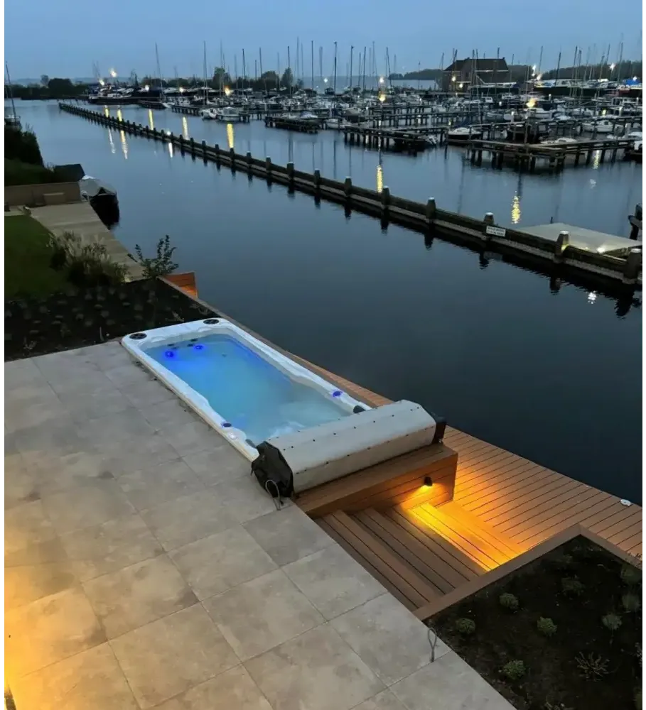 PassionSpa Aquatic 2 Swim-Spa – modernes Design, weißer Innenraum, blaue Beleuchtung, Holzterrasse, am Wasser