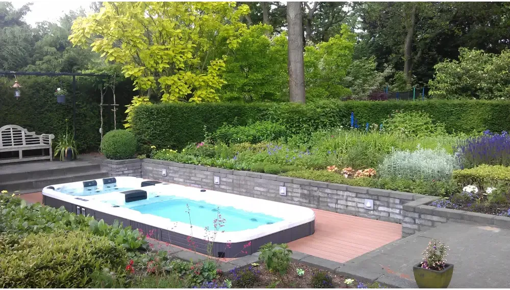 PassionSpa Aquatic 3 Deep Swim-Spa – rechteckige Form, weißer Innenraum, dunkelgraue Oberfläche, Holzterrasse, umgebendes Grün