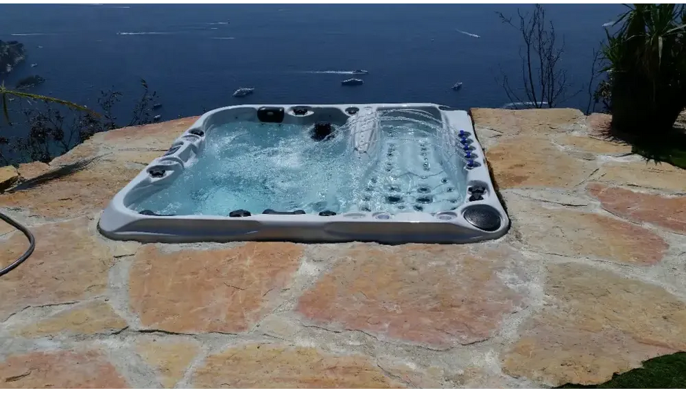 PassionSpa Euphoria Mighty Wave Whirlpool – graue Ausführung, schwarze Massagedüsen, Steinterrasse, am Meer