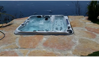 PassionSpa Euphoria Mighty Wave Whirlpool – graue Ausführung, schwarze Massagedüsen, Steinterrasse, am Meer