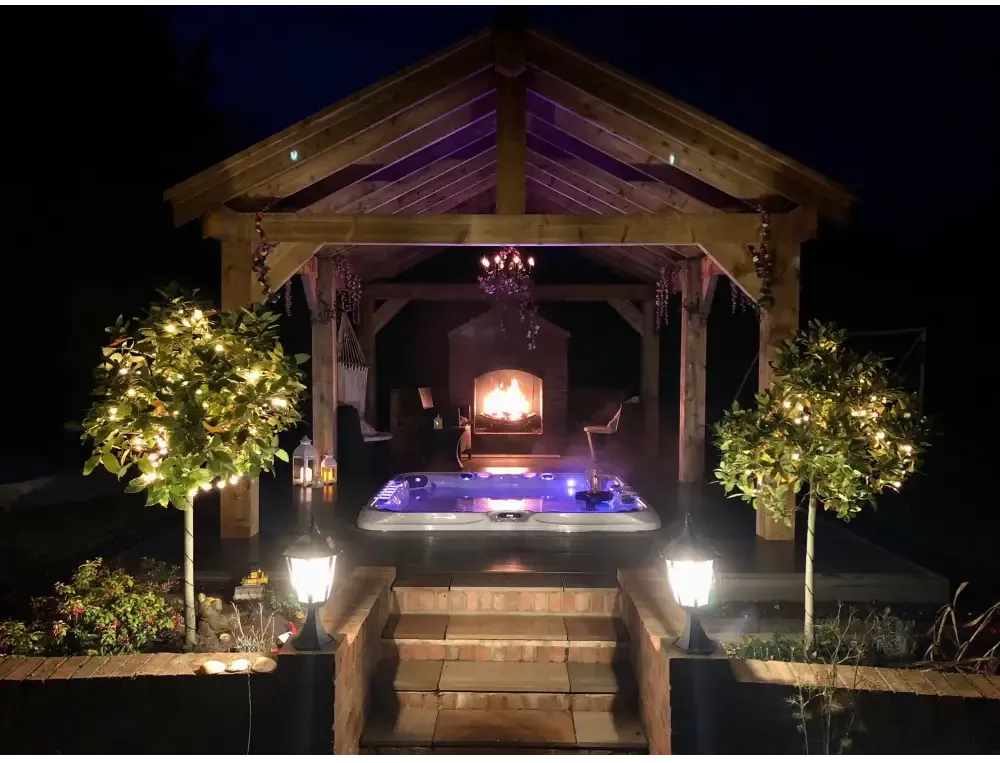 PassionSpa Excite Mighty Wave Whirlpool – blaue Beleuchtung, Holzdach, bei Nacht