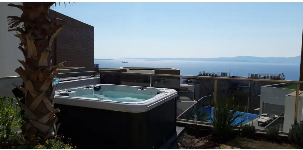 PassionSpa Relax Whirlpool – Pure Collection, schwarze Ausführung, blaues Wasser, auf einer Dachterrasse, Meerblick