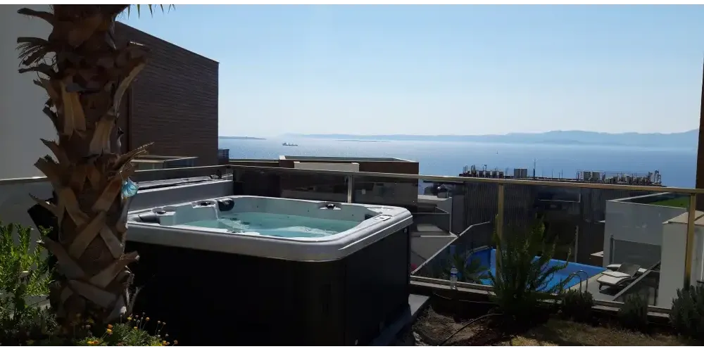 PassionSpa Relax Whirlpool – Pure Collection, schwarze Ausführung, blaues Wasser, auf einer Dachterrasse, Meerblick