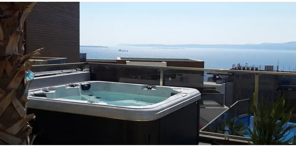 PassionSpa Relax Whirlpool – Pure Collection, weiß und schwarz, auf einem Balkon, Meerblick