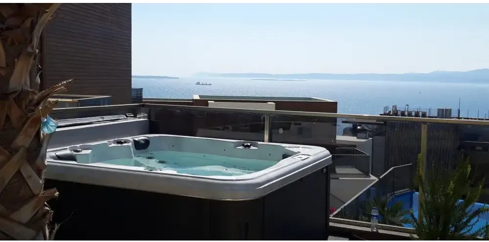 PassionSpa Relax Whirlpool – Pure Collection, weiß und schwarz, auf einem Balkon, Meerblick