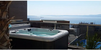PassionSpa Relax Whirlpool – Pure Collection, weiß und schwarz, auf einem Balkon, Meerblick