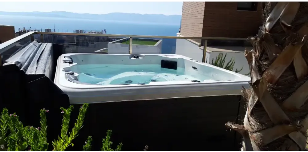 PassionSpa Relax Whirlpool – Pure Collection, weiße Ausführung, auf einem Balkon, Meerblick