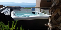 PassionSpa Relax Whirlpool – Pure Collection, weiße Ausführung, auf einem Balkon, Meerblick