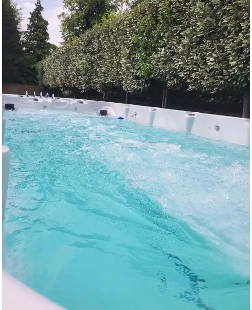 PassionSpa Spirit Swim-Spa – weiße Ausführung, türkisfarbenes Wasser, Massagedüsen, grüne Bäume