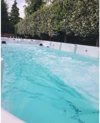 PassionSpa Spirit Swim-Spa – weiße Ausführung, türkisfarbenes Wasser, Massagedüsen, grüne Bäume