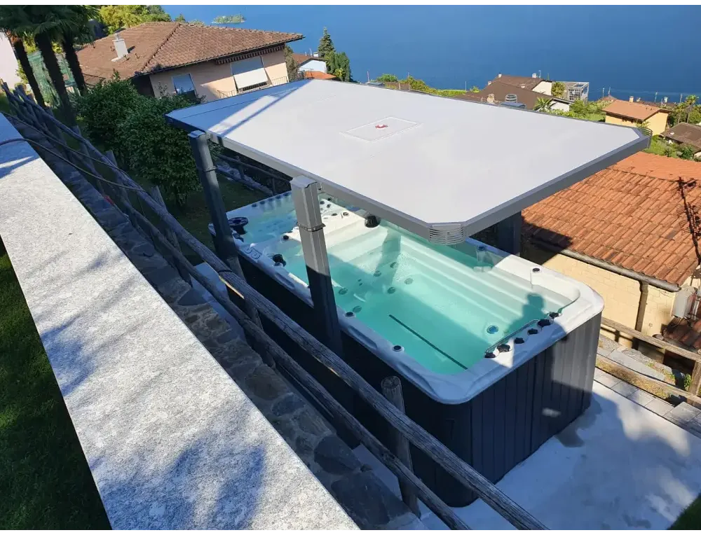 PassionSpa Spirit Swim-Spa – graue Ausführung, weiße Abdeckung, schwarze Massagedüsen, Steinterrasse, am Meer