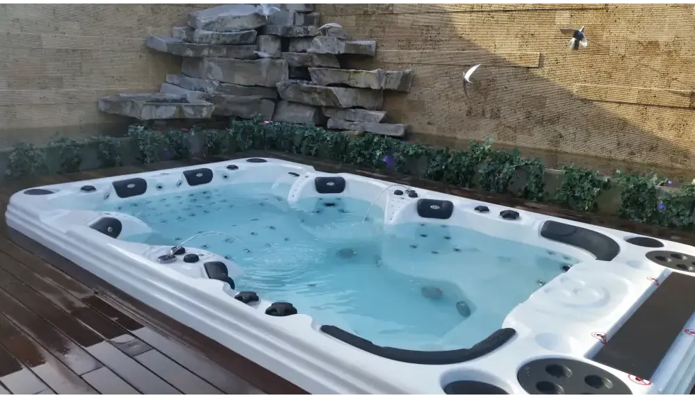 Vitvitt spabad PassionSpa Theater Spabad med svarta säten och jetmunstycken mot stenval