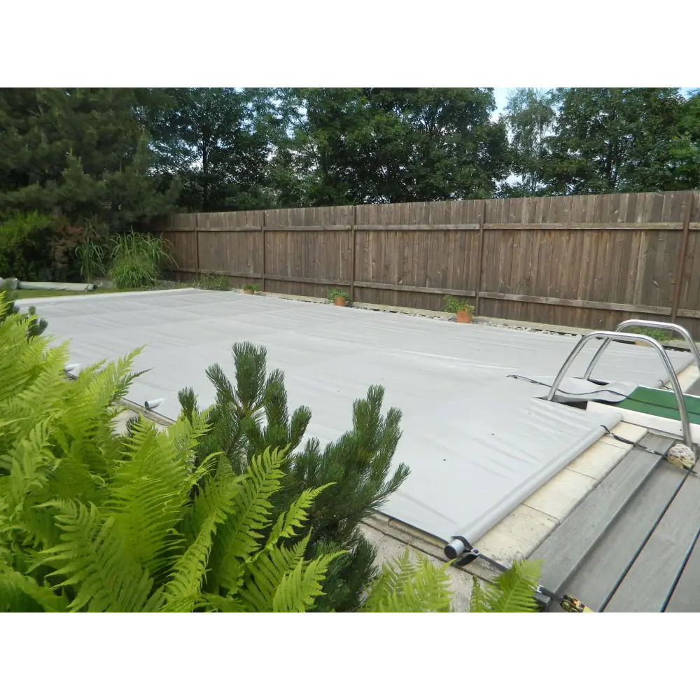 Grå pooltäckning med metallram, inkl handenhet, gröna växter i förgrunden